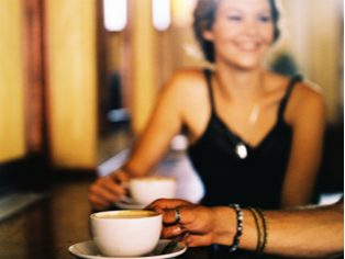 close up of two cups of coffee and young people chatting in a coffee shop
