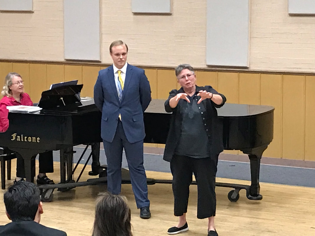 Masterclass session with teacher using hands to explain next to singer and piano